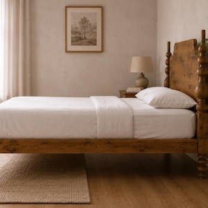 Könnte beinhalten: Ein Holzbettgestell mit natürlichem braunen Finish, ausgestattet mit einem hohen Kopf- und Fußteil mit gedrechselten Pfosten im Spindelstil. Das Bett ist mit einer weißen Matratze, einem weißen Betttuch und einem weißen Kissen bezogen.