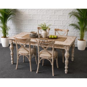 Handgemaakte eethoek in boerderijstijl van massief hout, met een verweerde tafel en gestoffeerde stoelen met kruisrugleuning.