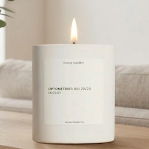 May include: A lit white soy wax candle with the text "sunny candles" and "OPTOMETRIST: BIG 20/20 ENERGY" on the label. The candle is 9 oz and sits on a wooden surface.
