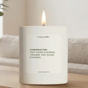 May include: A lit white soy wax candle with the text "CHIROPRACTOR: THAT SOUND IS NORMAL. I PROMISE THAT SOUND IS NORMAL." The candle is 9 oz and from Sunny Candles. The candle is on a wooden surface.