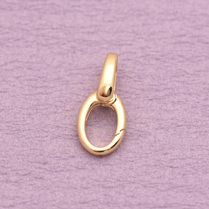 May include: A polished gold-tone metal oval-shaped jewelry clasp featuring a hinged mechanism. The component has a smooth, reflective surface and a small loop at the top for attachment, designed as a functional connector for necklaces or bracelets.