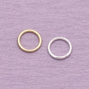 May include: Two circular rings, one in a polished gold tone and one in a polished silver tone. Both rings feature a smooth, continuous band with a simple, rounded profile. The two metal rings are positioned side by side, showcasing their metallic finish.