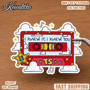 May include: A rectangular sticker featuring a red cassette tape design with the text "I KNEW IT, I KNEW YOU" and "TS". The design includes a yellow star with the number 13, white clouds, yellow stars, and musical notes on a light blue background.