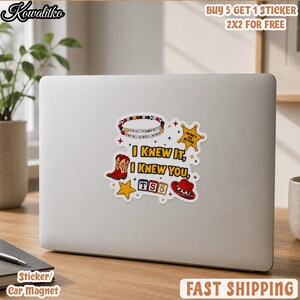 May include: A white sticker on a laptop featuring the text I KNEW IT, I KNEW YOU, TS5, and INFINITY AND BEYOND. The design includes a beaded bracelet, a yellow star, a red cowboy boot, a red cowboy hat, and colorful alphabet blocks.
