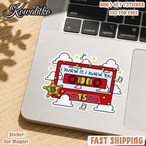 May include: A rectangular red cassette tape sticker featuring the text "I KNEW IT, I KNEW YOU" and "TS". The design includes a yellow star with the number 13, white clouds, musical notes, and small yellow stars against a white background.