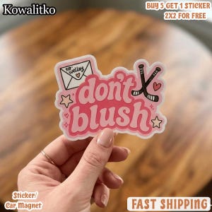 May include: A die-cut sticker featuring the pink text don't blush in a bold font. The design includes a white envelope with the text xo: wellsy and a heart, two crossed black hockey sticks, small stars, and hearts on a white background.
