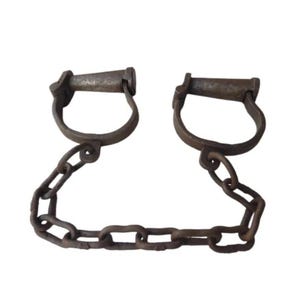 Puede incluir: Un par de grilletes metálicos antiguos, con dos esposas en forma de D conectadas por una cadena. El metal tiene una apariencia desgastada y envejecida, lo que sugiere un uso histórico. El fondo es blanco.