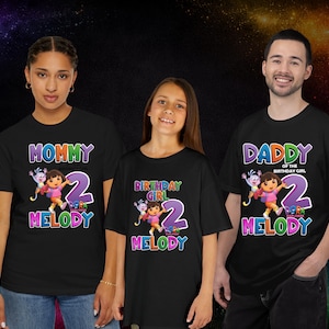 May include: Black t-shirts with colorful graphics for a family. The shirts feature the text "MOMMY", "BIRTHDAY GIRL", and "DADDY OF THE BIRTHDAY GIRL" with the number "2" and the name "MELODY", along with a cartoon character.