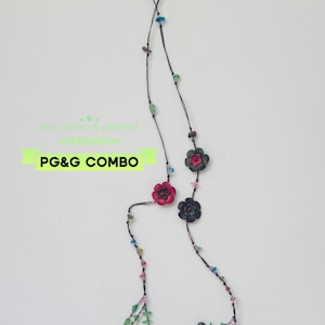 May include: A long necklace on a thin dark cord featuring scattered small colorful beads and several carved flower-shaped charms in shades of pink, green, and dark gray. The text "pink, green & greener combinations" and "PG&G COMBO" is visible.