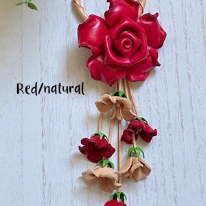 May include: A leather keychain with a red rose and a dangling chain of red and beige flowers. The text "Red/natural" is visible in the image.