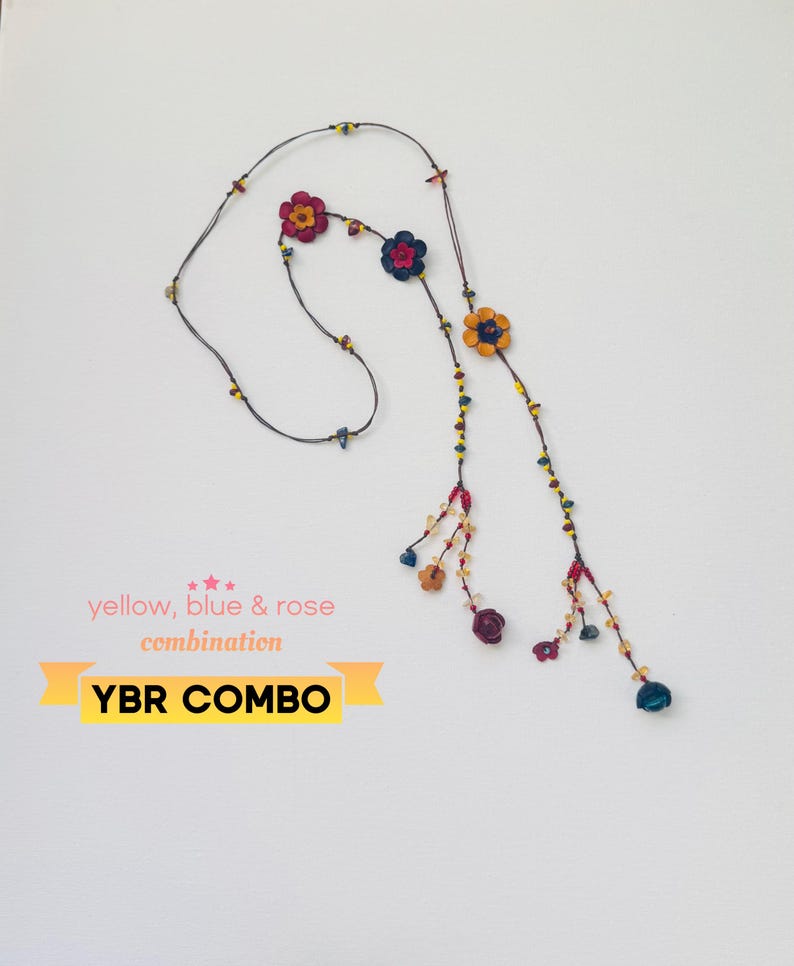 May include: A long necklace featuring a dark cord adorned with small multi-colored beads and several flower-shaped charms in shades of yellow, blue, and rose. The text on the image reads: yellow, blue & rose combination YBR COMBO.