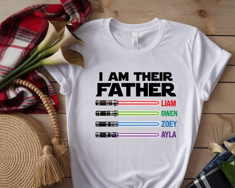 Pu&ograve; includere: Maglietta bianca con la scritta nera "I AM THEIR FATHER". Sotto, quattro spade laser con raggi rossi, verdi, blu e viola, ciascuna con un nome: Liam, Owen, Zoey e Ayla.