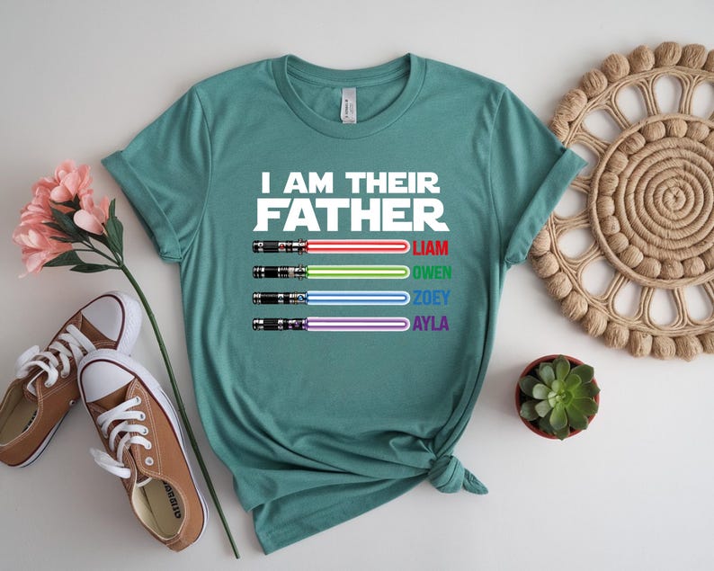 Pu&ograve; includere: T-shirt verde acqua con la scritta "I AM THEIR FATHER" e quattro disegni di spade laser colorate. Sotto, i nomi Liam, Owen, Zoey e Ayla. La maglietta &egrave; presentata con scarpe da ginnastica marroni e un fiore.