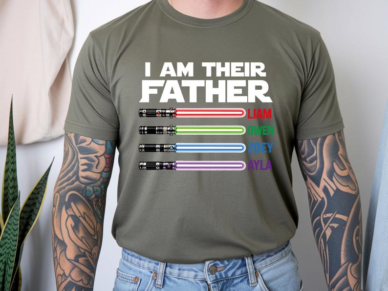 Pu&ograve; includere: T-shirt verde oliva con la scritta bianca "I AM THEIR FATHER". Sotto, quattro spade laser con i nomi Liam, Owen, Joey e Ayla in diversi colori. Le spade laser hanno lame rosse, verdi, blu e viola.