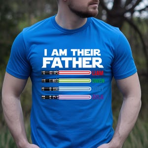 Pu&ograve; includere: Una maglietta blu con la scritta bianca "I AM THEIR FATHER". Sotto, quattro spade laser colorate con i nomi: Liam, Owen, Zoey e Ava. Le spade laser sono rosse, verdi, blu e viola.