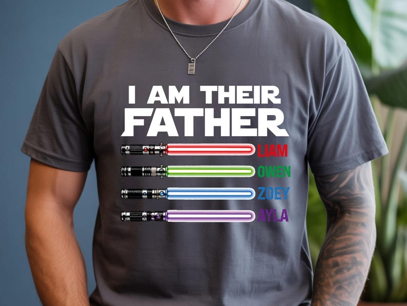 Pu&ograve; includere: T-shirt grigia con la scritta bianca "I AM THEIR FATHER". Sotto, quattro spade laser rosse, verdi, blu e viola, con i nomi Liam, Owen, Zoey e Ayla. La maglietta &egrave; girocollo.