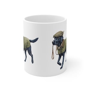Puede incluir: Taza de cerámica blanca con una ilustración a la acuarela de un Labrador Retriever negro. El perro lleva una chaqueta acolchada, una gorra de tweed y una bufanda, y sujeta una correa de cuero. La taza tiene forma cilíndrica.