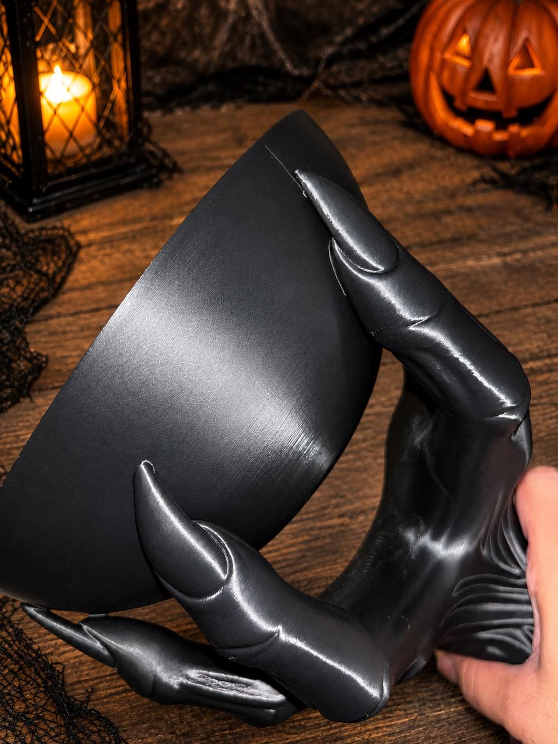 Creepy hand candy bowl holding assorted Halloween candies on a dark table.