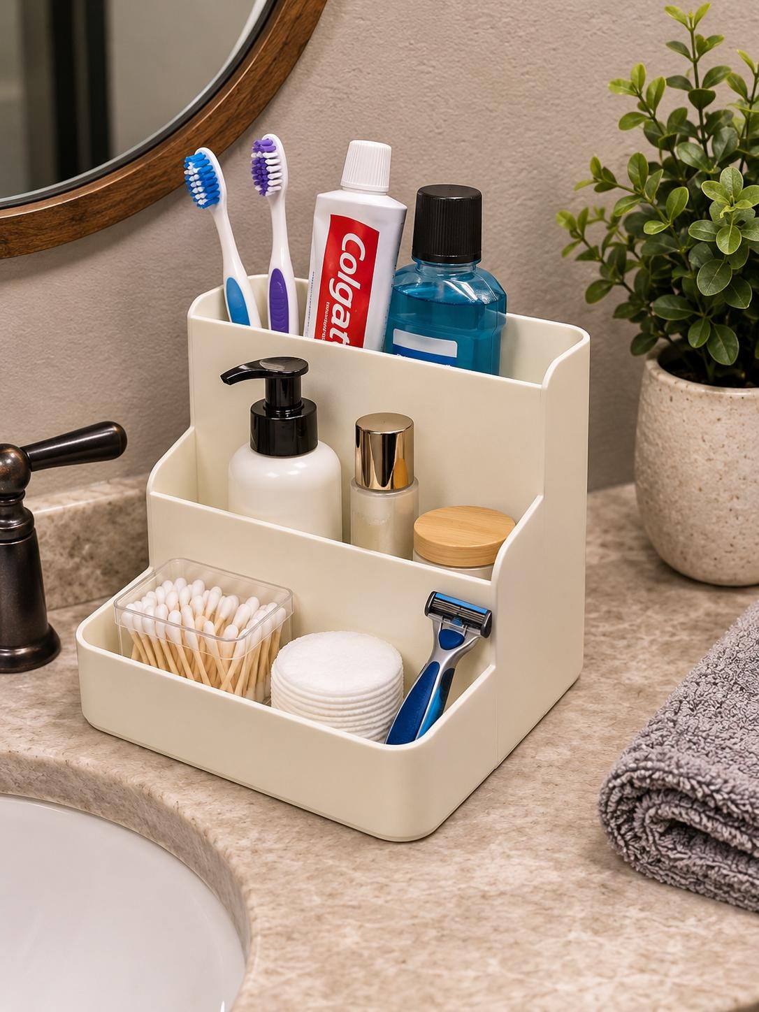 A beige three tier organizer caddy on a bathroom counter holding toothbrushes, toothpaste, and skincare.