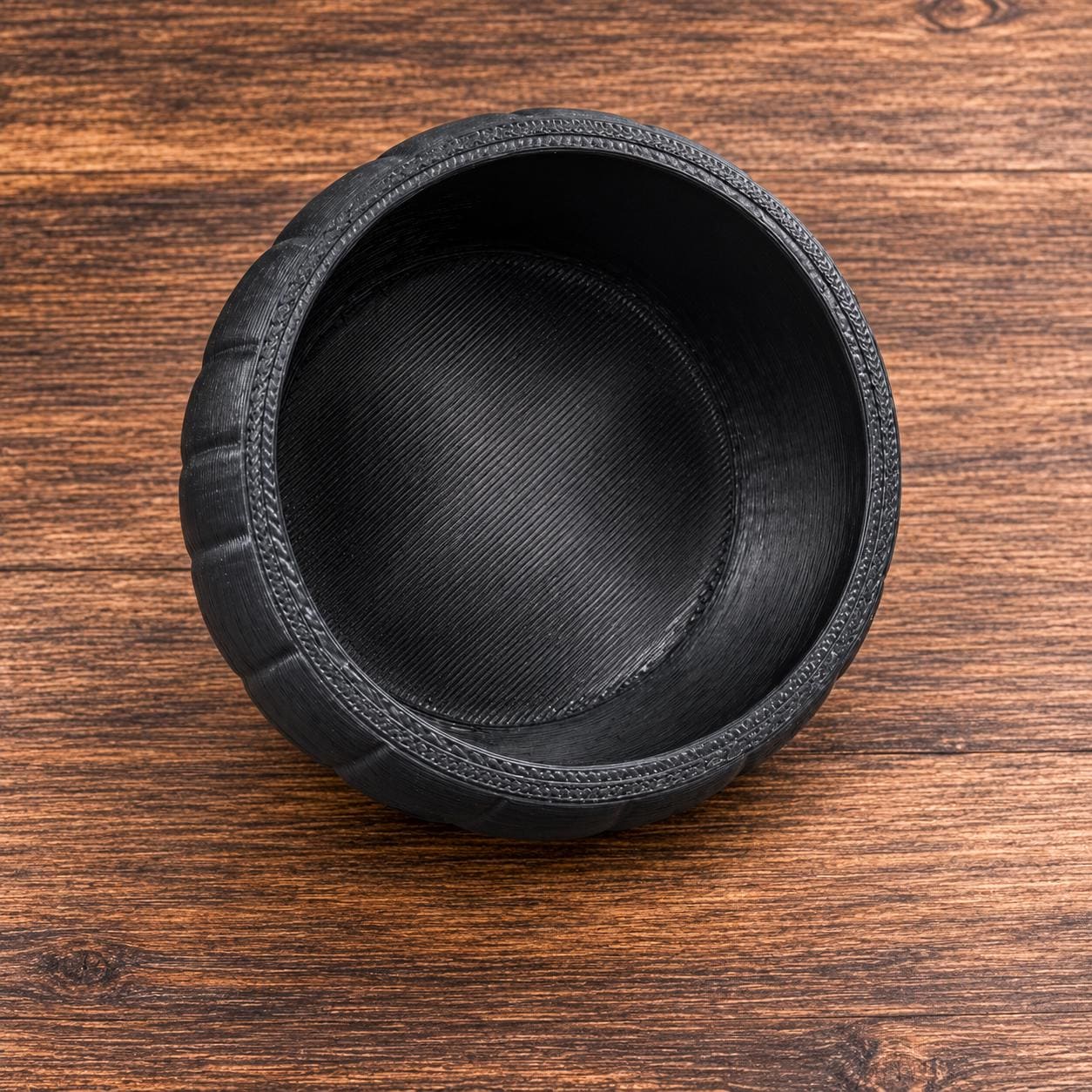 The inside of a black, 3D printed jack-o'-lantern candy bowl, showing the ribbed interior.