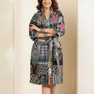 May include: A patchwork robe with a V-neck and a tie belt. The robe features a variety of patterns and colors, including black, white, pink, and blue. The robe is knee-length and has short sleeves. The model is wearing silver bracelets and earrings.