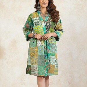 May include: A patchwork robe in shades of green, yellow, and blue. The robe features a V-neck and three-quarter sleeves. The fabric is made of various patterned squares sewn together. The robe is knee-length and has a matching belt.