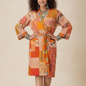 Pode incluir: Robe patchwork em tons de laranja, vermelho e amarelo. O robe apresenta um design envolvente com cinto a condizer. As mangas são compridas e largas. O robe é feito de uma variedade de quadrados de tecido estampados.