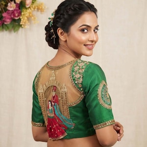 Puede incluir: Una blusa verde esmeralda vibrante con un panel trasero de tul beige y bordados dorados intrincados. El diseño muestra una ilustración cosida detallada de dos figuras con vestimenta tradicional enmarcadas por un arco, con detalles de lentejuelas doradas.