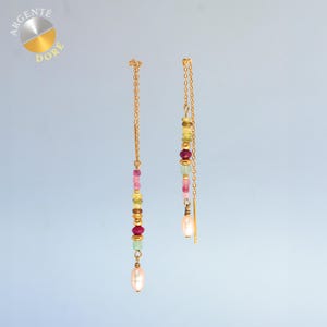 Peut inclure: Une paire de boucles d'oreilles pendantes en chaîne dorée avec un alignement vertical de petites perles multicolores dans des tons rose, jaune, vert et rouge, terminées par une perle ovale blanche au bas de chaque brin de boucle.