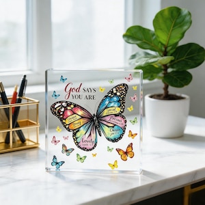 May include: A clear acrylic block featuring a large, colorful butterfly with text on its wings that reads Unique, Strong, Lovely, Special, Precious, and Chosen, along with the phrase God says you are and several smaller butterflies.