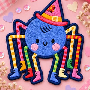 May include: An embroidered patch featuring a round blue spider with a smiling face, pink cheeks, and a pointed pink witch hat. The spider has eight long legs, each with a different colorful pattern of stripes or dots, and each leg ends in a small boot.