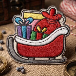May include: An embroidered patch featuring a red Santa sleigh filled with colorful gift boxes and a red sack. The sleigh has a white trim and grey runners. The gifts are wrapped in purple, blue, green, and yellow paper with blue bows.