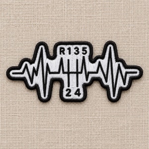 May include: An embroidered patch featuring a black and white design that combines a heartbeat EKG line with a manual transmission gear shift pattern. The center displays the shift layout with R, 1, 3, 5 on top and 2, 4 on the bottom in black.