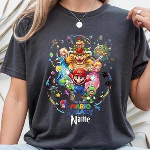 May include: A white ceramic mug with a black handle and the text "But First, Coffee" in a bold, black font. The mug is filled with a dark liquid, likely coffee, and rests on a light-coloured surface.