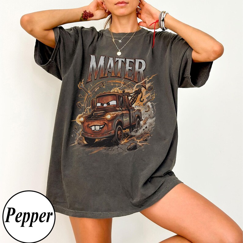 Puede incluir: Camiseta gris oscuro con una imagen de dibujos animados de Mate de la pel&iacute;cula Cars. La palabra "MATER" est&aacute; impresa encima de la imagen en un estilo desgastado. El gr&aacute;fico incluye rayos y un fondo desgastado.