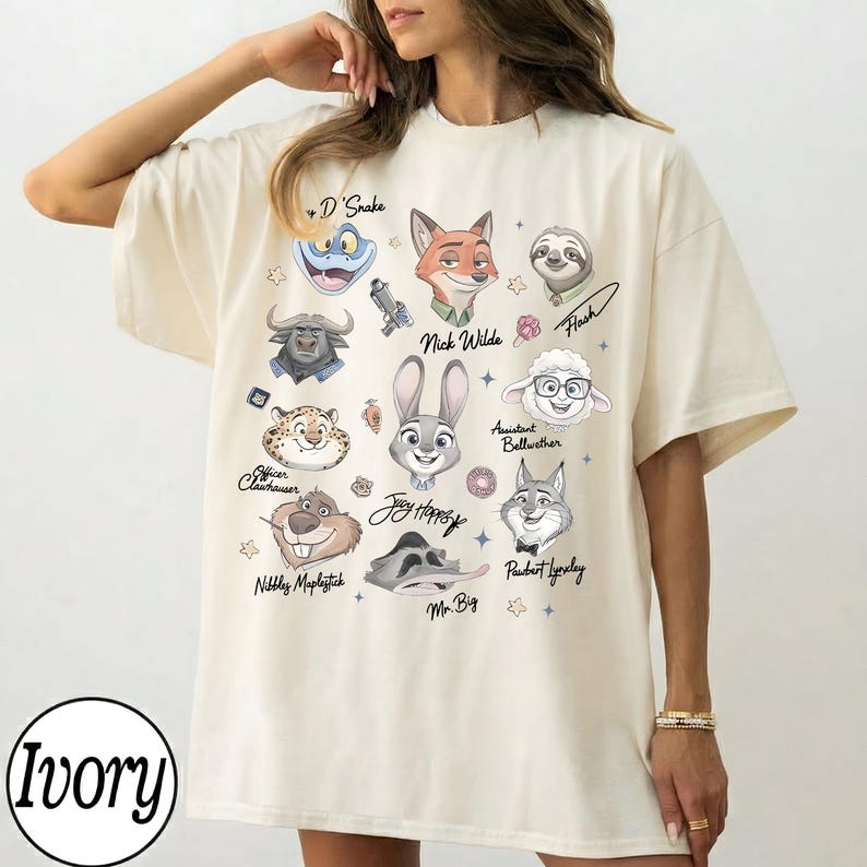 Może przedstawiać: Kremowa koszulka oversize z ilustracjami postaci z kresk&oacute;wek. Koszulka zawiera postacie takie jak Nick Wilde, Judy Hopps i Flash. Słowo "Ivory" jest wydrukowane w lewym dolnym rogu.
