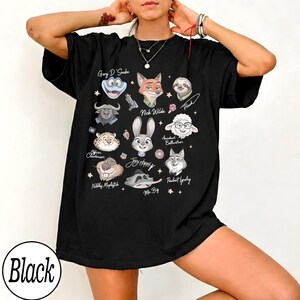 Może przedstawiać: Czarna koszulka z ilustracjami postaci z kresk&oacute;wek z filmu. Koszulka zawiera postacie takie jak Nick Wilde, Judy Hopps i Flash. Słowo "Black" jest wydrukowane w białym okręgu na dole.