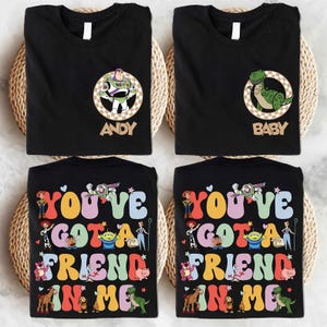May include: Four black t-shirts with Toy Story designs. Two shirts feature character portraits with names, and the other two display the phrase "You've Got a Friend in Me" with various characters from the film.
