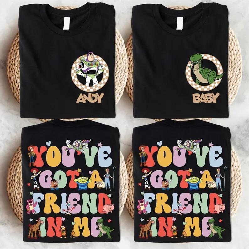 May include: Four black t-shirts with Toy Story designs. Two shirts feature character portraits with names, and the other two display the phrase "You've Got a Friend in Me" with various characters from the film.