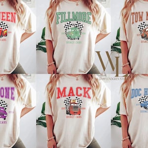 May include: Cream-colored t-shirts featuring various Disney Cars characters: McQueen, Fillmore, Tow Mater, Ramone, Mack, and Doc Hudson. Each shirt displays the character's name, a checkered flag, and the text "Disney Cars".