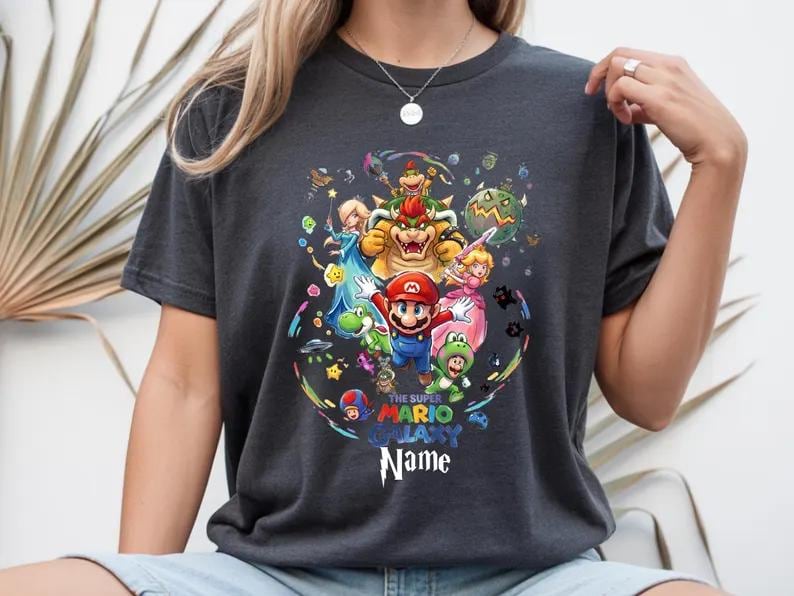 May include: A white ceramic mug with a black handle and the text "But First, Coffee" in a bold, black font. The mug is filled with a dark liquid, likely coffee, and rests on a light-coloured surface.