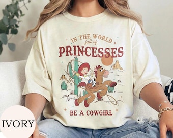 レトロなトイ・ストーリーのジェシーとブルズアイがプリンセスだらけの世界でカウガールになるTシャツ、ディズニーのウエスタンカウガールTシャツ、ディズニーランドガールトリップTシャツ