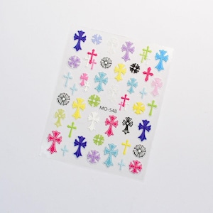 May include: Sheet of colourful cross-shaped nail art stickers. The stickers are in various colours, including pink, blue, yellow, and white. Some stickers have floral accents. The sheet has the text "MO-548".