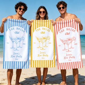 May include: Three rectangular beach towels featuring vertical stripes in blue, yellow, and coral. Each towel displays a central arch graphic with martini glasses, the text "THE BRIDE Club", "Est 2026", "Liora's Hen Party", and "Ibiza".