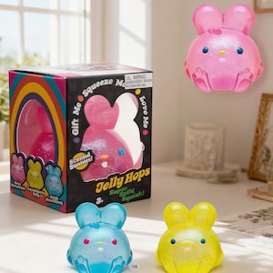 May include: A selection of scented bunny-shaped toys in pink, blue, and yellow. The toys are labelled "Jelly Hops" and "Super Solid Squish!". A box with a rainbow design and the words "Gift Me" and "Love Me" is also present.