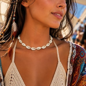 May include: A choker necklace composed of a single strand of white cowrie shells strung together. The shells are uniform in size and shape, creating a continuous circular band that rests around the base of the neck.
