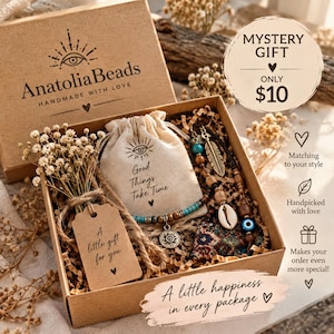 Könnte beinhalten: Eine braune Geschenkschachtel aus Karton mit einem kleinen beigen Beutel mit der Aufschrift Good Things Take Time, einem Perlenarmband mit Sonnenanhänger, einer Kaurimuschel, einem Metallfederanhänger und einem Anhänger A little gift for you.