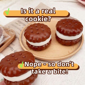 May include: Brown, round, faux cookies with white filling, arranged on a wooden tray and a white surface. The text on the image says, "Is it a real cookie?" and "Nope - so don't take a bite!"