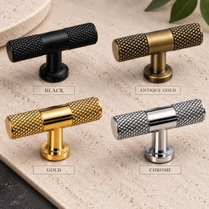May include: Four T-bar cabinet knobs with a knurled texture on the ends and a smooth center. The finishes include black, antique gold, gold, and chrome. Each knob is labeled with its respective color name: Black, Antique Gold, Gold, and Chrome.