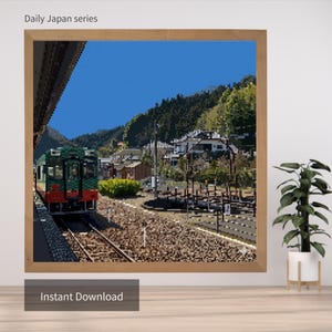 以下が含まれることがあります： ピクセル化された駅のシーンの額入りプリント。電車は緑と赤で、背景には青い空と緑の丘があります。「Daily Japan series」という文字が上部に、「Instant Download」という文字が下部にあります。